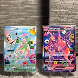 Könnte beinhalten: Zwei Pokémon-Sammelkarten in Schutzhüllen. Die linke Karte ist ein hellblaues Mew ex mit 160 KP, ausgestattet mit der Fähigkeit Memory Helix und der Attacke Teleportation Burst. Die rechte Karte ist ein violettes Mewtwo ex mit 230 KP, mit den Attacken Photon Bullets und Psychic Powers.