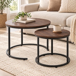 May include: A set of two round nesting coffee tables featuring dark brown wood-grain laminate tops and black metal frames. The larger table holds a small potted plant on a book, while the smaller table holds a ceramic mug on a wooden coaster.