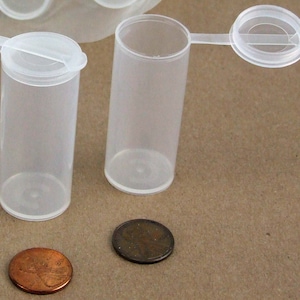 May include: Two clear plastic containers with lids. The containers are about the size of a UK penny. The lids have a small tab for easy opening.