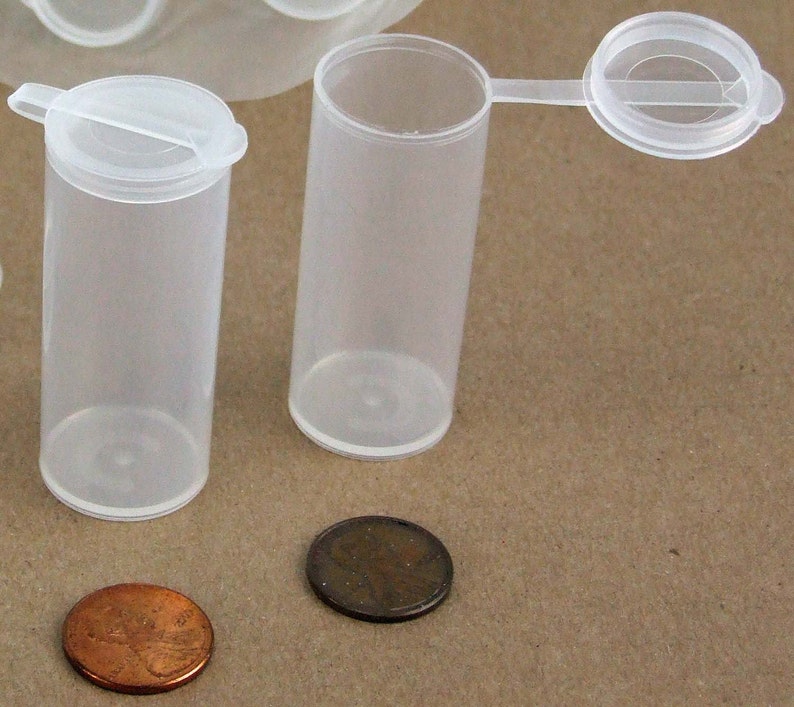 May include: Two clear plastic containers with lids. The containers are about the size of a UK penny. The lids have a small tab for easy opening.