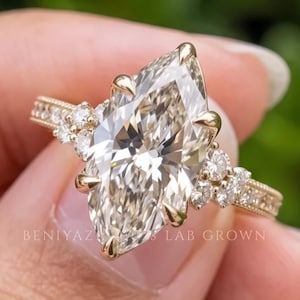 Hand held front view of a 3 carat marquise lab grown diamond engagement ring showing the elongated centre stone and ornate band.