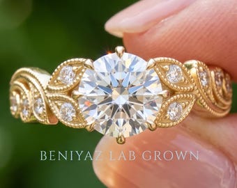 May include: A gold ring featuring a large round brilliant-cut centre stone surrounded by smaller round stones set in a leaf-like pattern along the band. The text BENIYAZ LAB GROWN is visible below the ring. The metal has a polished yellow finish.