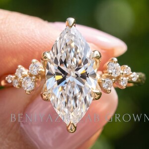 Marquise engagement ring with a lab grown diamond centre and round diamond clusters on a thin yellow gold band