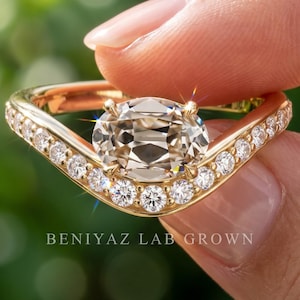 Hand holding a 1.66 CT antique style lab grown diamond engagement ring in yellow gold, featuring a marquise inspired chevron halo and vintage design
Antique engagement ring with an east west oval champagne lab grown diamond on a curved pave yellow gold band