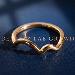 Curved V contour wedding band in yellow gold worn with an engagement ring, showing the 2mm chevron nesting shape on hand.