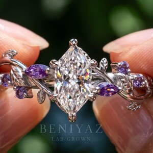 May include: A silver-toned ring featuring a central marquise-cut clear stone flanked by smaller purple stones and metal leaf motifs. The band has a vine-like design. The text BENIYAZ LAB GROWN is visible on the lower portion of the image.