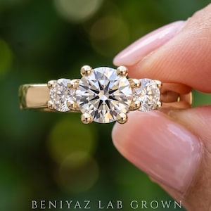 Three stone engagement ring with a round lab grown diamond and two round side diamonds in yellow gold
