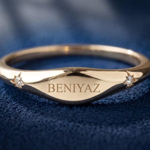 Personalized yellow gold signet ring engraved BENIYAZ with two small star-set lab grown diamond accents.