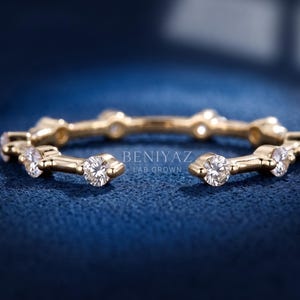 May include: A gold open-style ring featuring a series of evenly spaced, round, clear lab-grown diamonds set along the band. The text BENIYAZ LAB GROWN is visible in the center of the ring, which has a polished metallic finish and a circular shape.