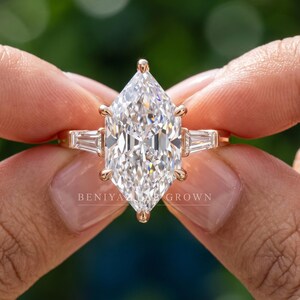 Close up Dutch marquise lab grown diamond ring held between fingers with bright elongated center and balanced side stones
