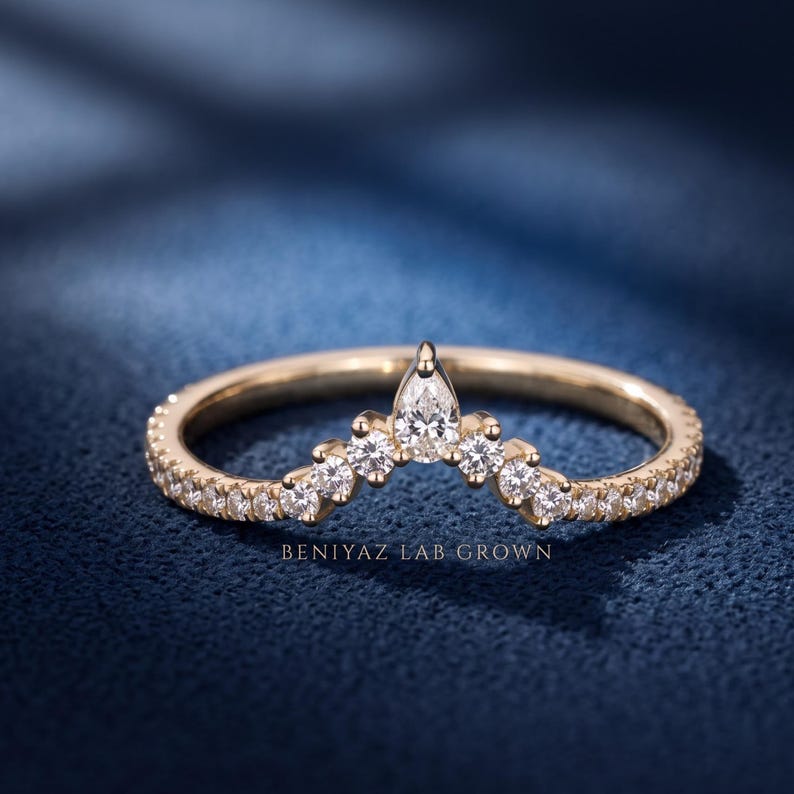 Curved lab grown diamond wedding band in yellow gold with a pear-shaped diamond at the apex, graduated round diamonds and a delicate contour design.