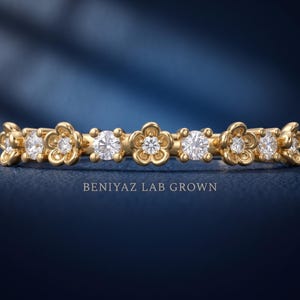 May include: A gold band ring featuring alternating round clear stones and five-petaled flower motifs. The text BENIYAZ LAB GROWN is printed below the ring. The design consists of a repeating pattern of circular gemstones set between gold flowers.