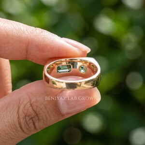 Hand displaying a two stone sapphire signet ring with teal emerald cut and round green sapphire, showing the polished band and low profile setting