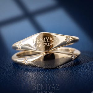 Two personalized yellow gold signet rings displayed together showing engraved and blank face options.