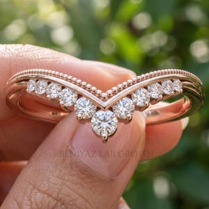 Front close view of V shaped moissanite wedding band with graduated round stones and crown inspired chevron design.