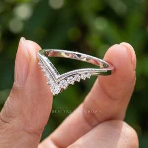 Side angle of moissanite chevron wedding band showing the curved contour design, graduated round stones and slim polished shank.