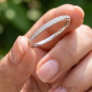 Angled close view of a half eternity pave ring with sparkling round stones and a slim polished band for stacking or anniversary wear.