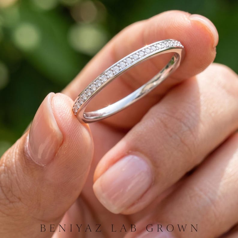 Angled close view of a half eternity pave ring with sparkling round stones and a slim polished band for stacking or anniversary wear.
