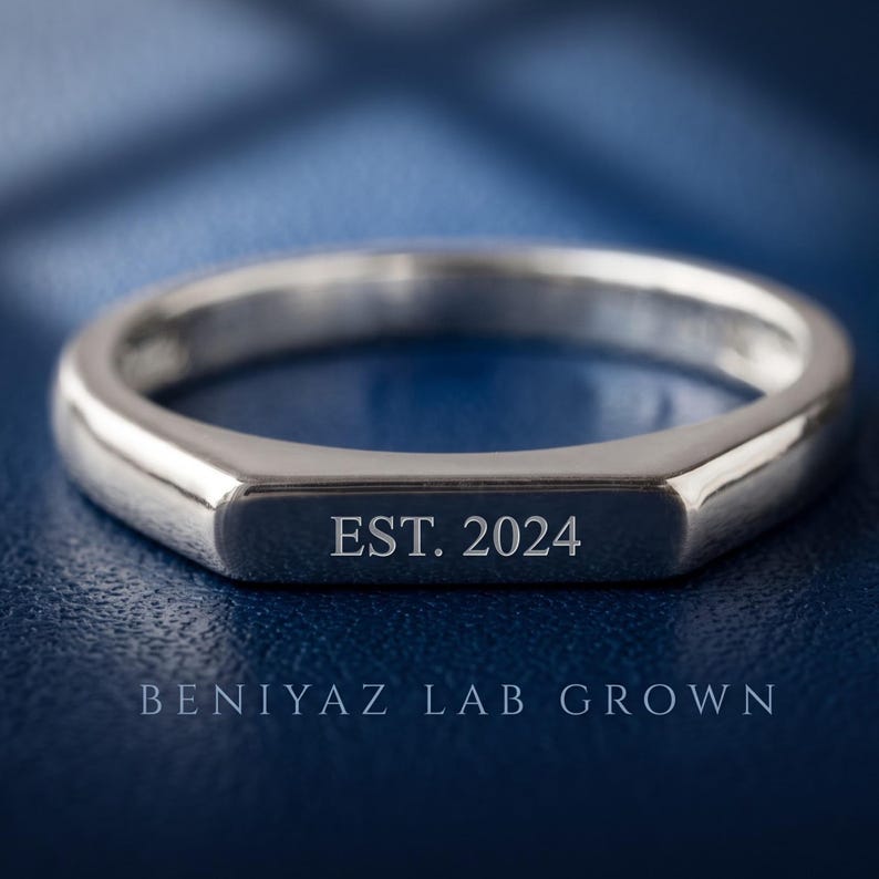 Minimalist flat top bar signet ring in polished silver tone shown from the front on a dark blue luxury background.