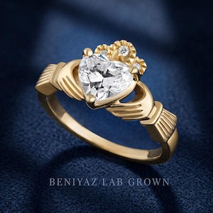 Heart cut Claddagh engagement ring worn on hand, showing the yellow gold band and symbolic crown, heart and hands design.