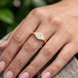 Engraved signet ring style shown on hand with celestial star motif, round diamond center and high polish gold finish.