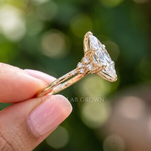 Side angle of marquise engagement ring showing the elevated center diamond, detailed cluster shoulders and hidden accent stone.