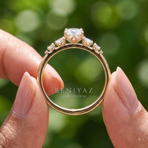 Close up worn view of a delicate lab grown diamond promise ring featuring a round center stone and thin solid gold band on hand