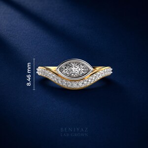 Two tone marquise lab grown diamond engagement ring featuring a bezel set center stone with curved pave diamond wedding band on luxury blue background.