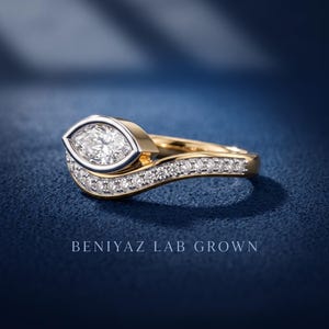Close-up of two tone marquise cut lab grown diamond ring set with curved pave wedding band, polished yellow and white gold bridal jewelry design.