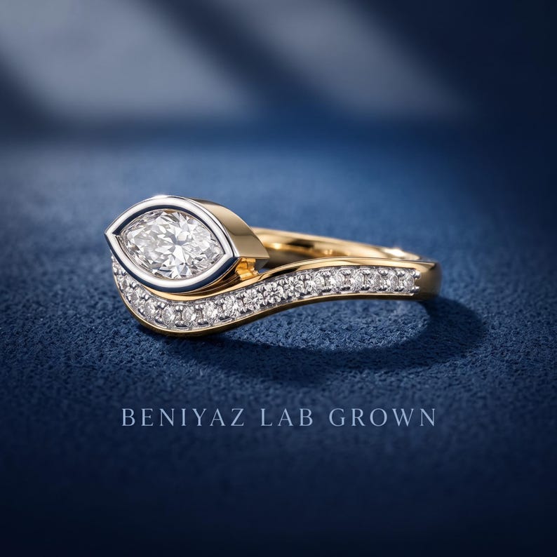 Close-up of two tone marquise cut lab grown diamond ring set with curved pave wedding band, polished yellow and white gold bridal jewelry design.