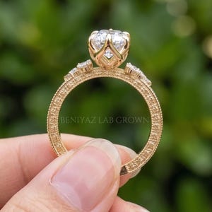 Close up outdoor view of a vintage inspired marquise engagement ring with a large lab grown diamond centre and ornate shoulders.