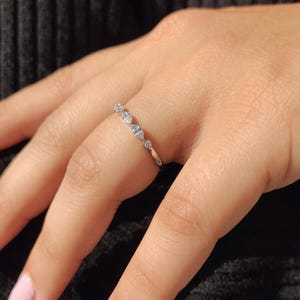 East west marquise wedding band with lab grown marquise and round diamonds, half eternity band held between fingers