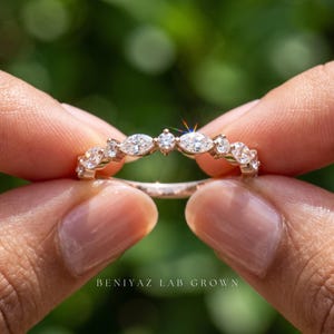 Side view of marquise and round diamond wedding band on blue background showing slim polished shank and delicate setting