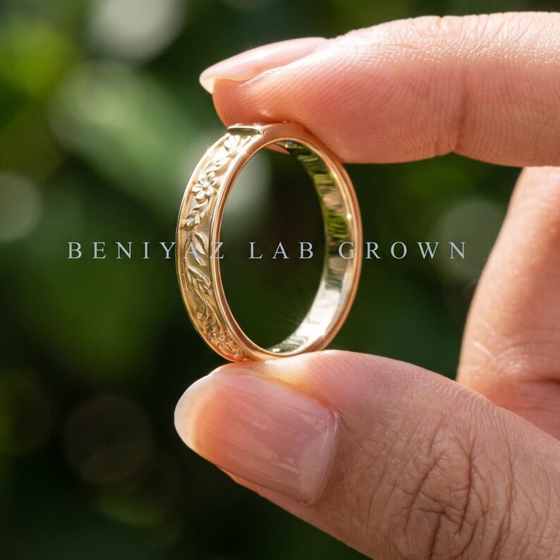 Puede incluir: Un anillo de oro con un intrincado patr&oacute;n floral y de hojas en relieve a lo largo de la banda exterior. El texto BENIYAZ LAB GROWN est&aacute; impreso en el centro de la imagen. El anillo tiene un acabado pulido y una superficie interior lisa.