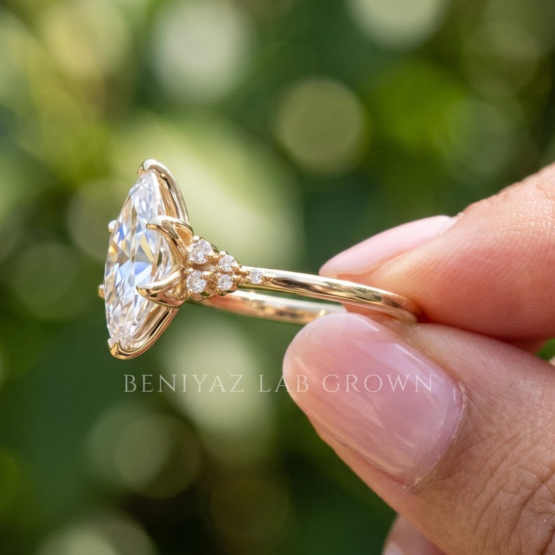 Three quarter side view of marquise lab grown diamond engagement ring showing the ornate setting and slim solid gold band.