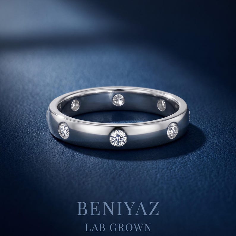 May include: A silver-toned metal band ring featuring multiple round, clear, bezel-set lab-grown diamonds spaced evenly around the circumference. The text BENIYAZ LAB GROWN is printed in white at the bottom of the frame.