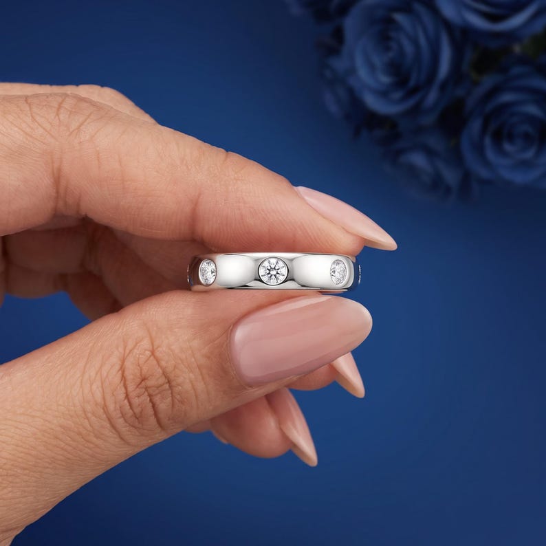 Two 14K white gold flush set lab grown diamond wedding bands on navy velvet. BENIYAZ.