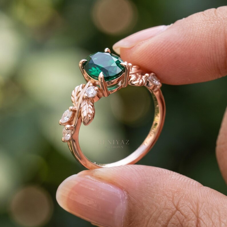Side profile of nature inspired emerald ring showing raised oval green gemstone setting, sculpted leaves and botanical branch shoulders.