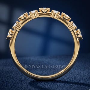 May include: A gold band ring featuring a series of small, clear, round-cut stones set along the top half of the band. Each stone is held in a prong setting. The text BENIYAZ LAB GROWN is visible in the center of the circular ring band.