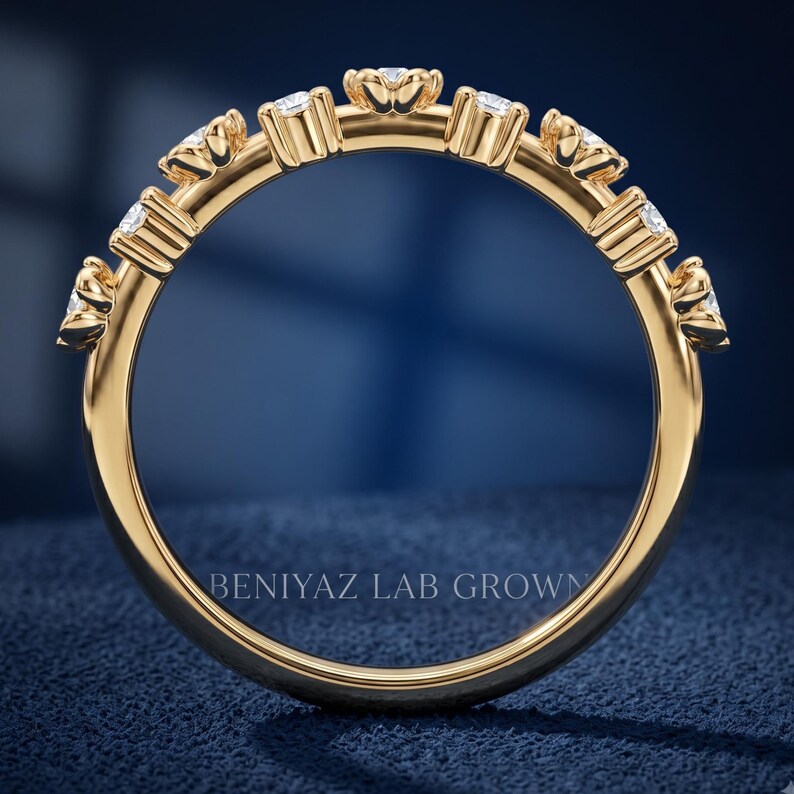 May include: A gold band ring featuring a series of small, clear, round-cut stones set along the top half of the band. Each stone is held in a prong setting. The text BENIYAZ LAB GROWN is visible in the center of the circular ring band.