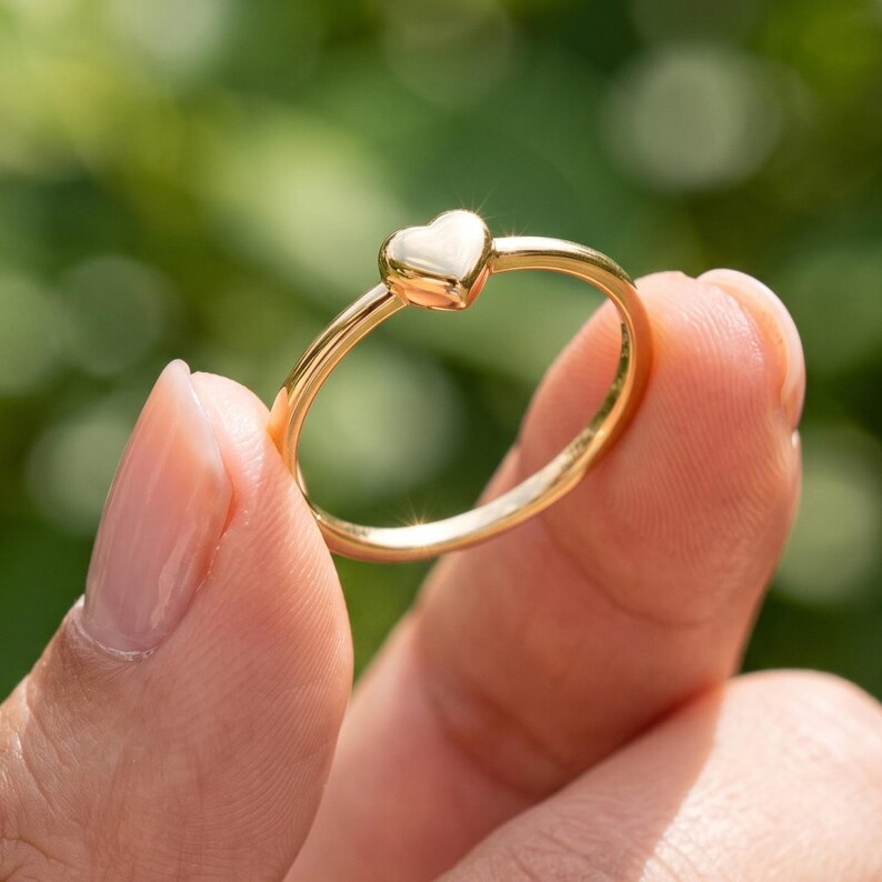 Dainty heart ring worn on hand, showing the minimalist polished heart design and slim everyday band.