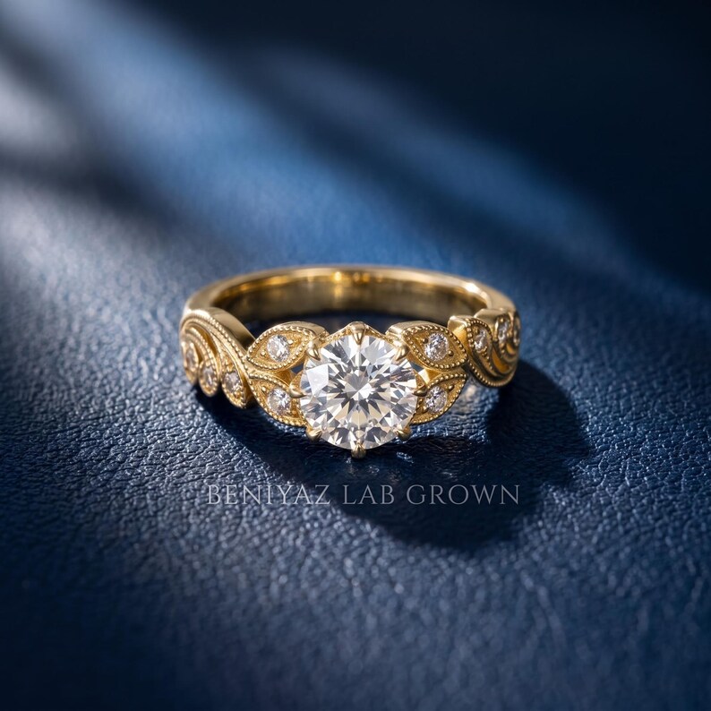 Yellow gold lab grown diamond engagement ring with a round brilliant center stone, vintage leaf and scroll design, milgrain accents and small round diamonds for added sparkle.