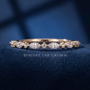 Front angle of marquise and round lab grown diamond band on blue background showing alternating prong set diamonds