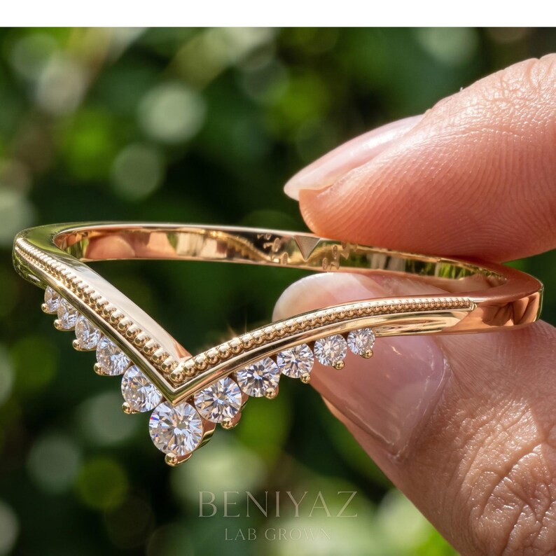 Angled close view of V shaped contour wedding band showing the graduated moissanite setting and curved bridal design.