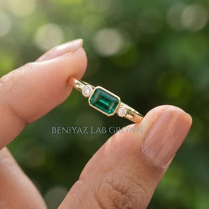 Angled profile of Art Deco inspired emerald cut ring with lab grown emerald center and round lab grown diamond side stones.