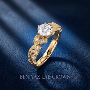 Angled white gold floral engagement ring with a large round lab grown diamond, detailed leaf shaped side settings, milgrain borders and sparkling diamond accents.