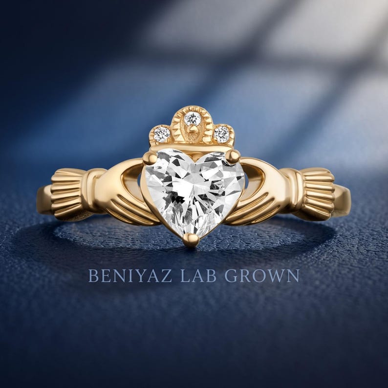 Front hand held view of a heart cut diamond Claddagh promise ring with traditional hands, heart and crown symbolism.