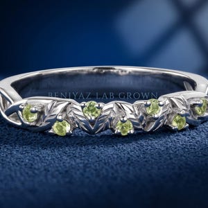 Nature inspired peridot leaf and vine ring with round green gemstones set in a sculpted botanical band.