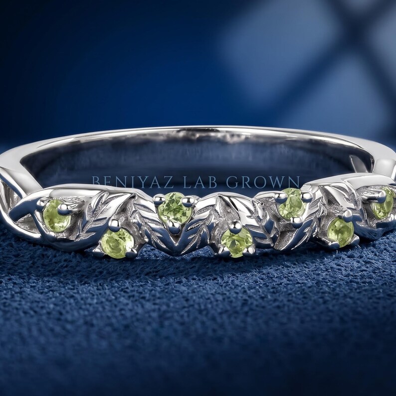 Nature inspired peridot leaf and vine ring with round green gemstones set in a sculpted botanical band.