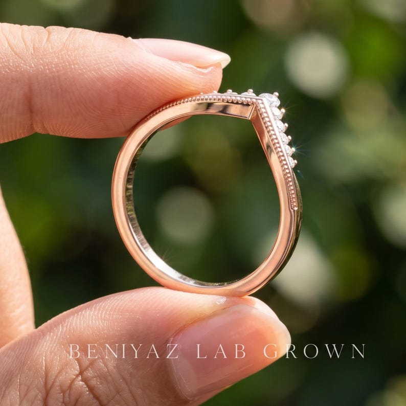 1. Full ring profile of moissanite nesting wedding band showing the polished shank and V shaped chevron front from the side.